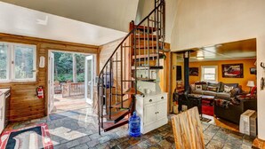 A wooden interior with a spiral staircase, a fireplace, and a view of the outdoors. - Riverside`s Hideout Cabin- With Hot Tub! (Lyons)