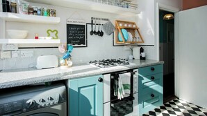 Une cuisine moderne avec des armoires de couleur turquoise, une cuisinière à gaz et un tableau noir où sont écrites des notes de cuisine.