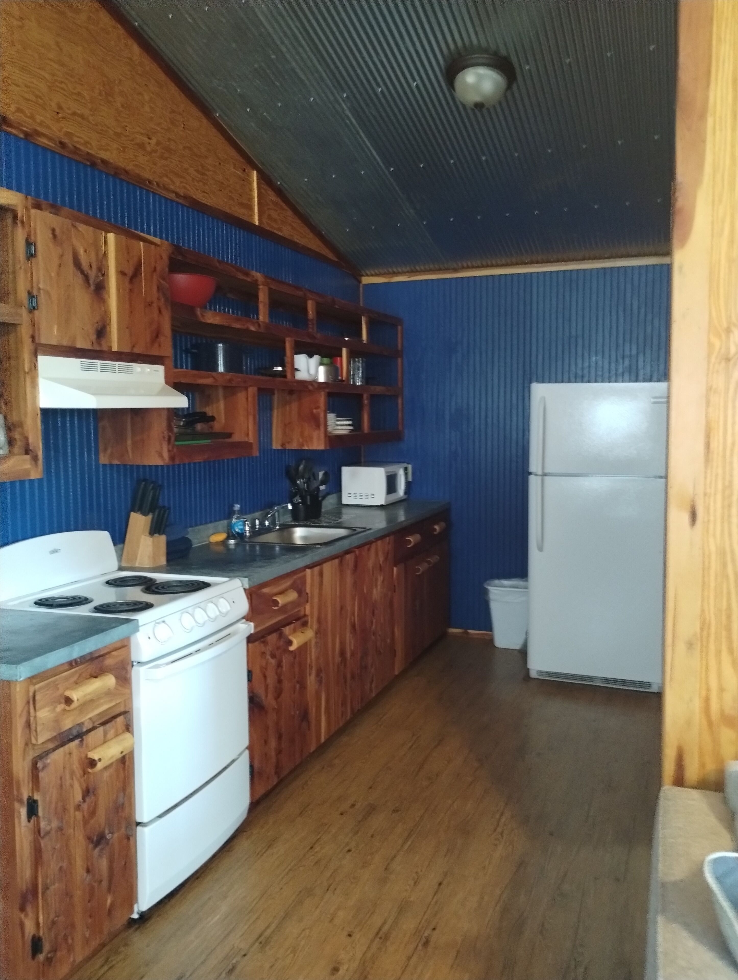 Una cucina con mobili in legno, piano cottura bianco, forno a microonde e frigorifero.