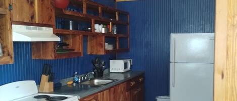 A kitchen with wooden cabinets, a white stove, a microwave, and a refrigerator.