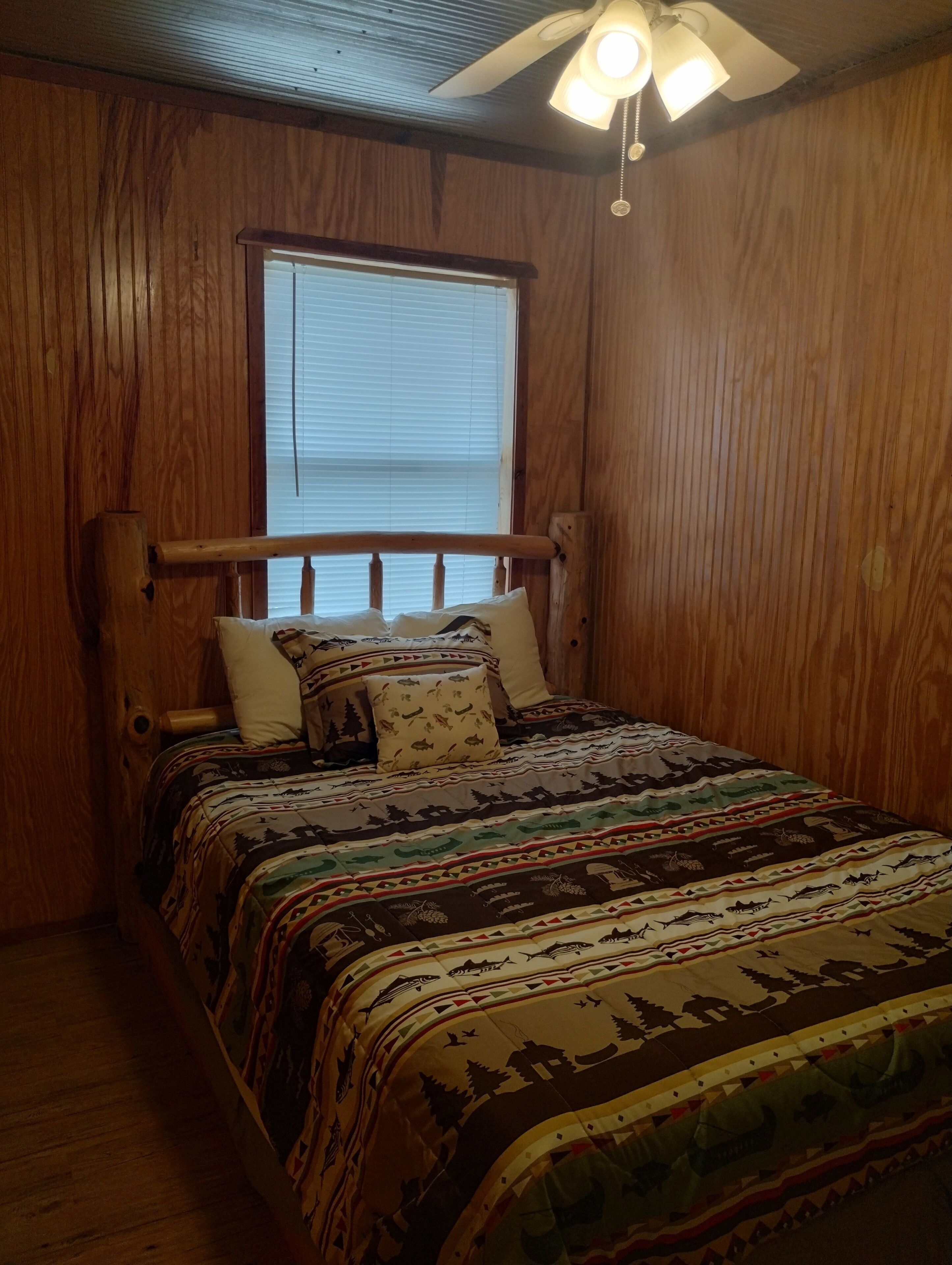 Una habitación con paneles de madera y una cama con colcha estampada.