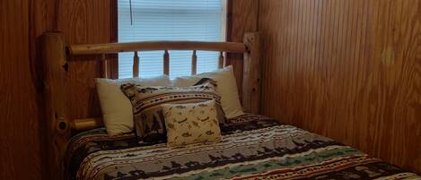 Una habitación con paneles de madera y una cama con colcha estampada.