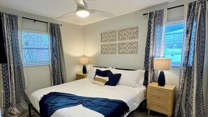A modern bedroom with a large bed, two bedside tables, a ceiling fan, and patterned curtains. - Modern Boho- 4/3-King Beds/Pool! Pet friendly! (Tampa)
