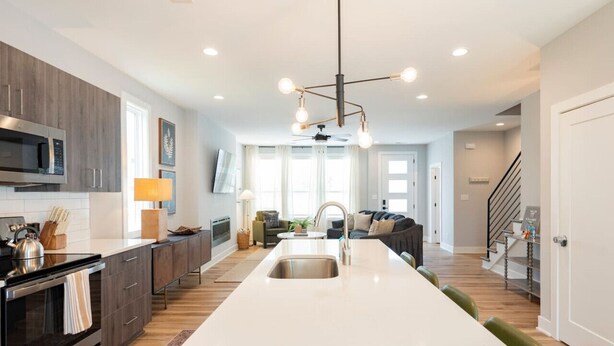 A modern kitchen with a central island, built-in appliances, and a pendant light fixture.