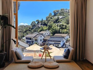 A room with a view of traditional houses on a hillside, a sofa, a small table, and a potted plant. - Hangzhou Moju Boutique Guesthouse  (Hangzhou)