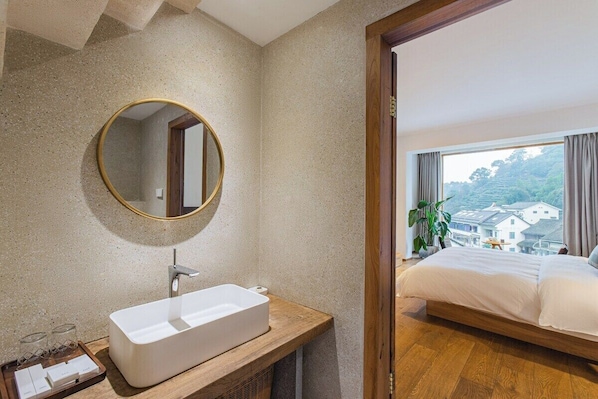 A modern bathroom with a freestanding sink, a round mirror, and a wooden vanity. - Hangzhou Moju Boutique Guesthouse (Hangzhou)