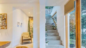 Ein modernes Interieur mit einer Treppe, die zu einem Balkon führt, einem Holzstuhl und einer Wand mit Fotos.