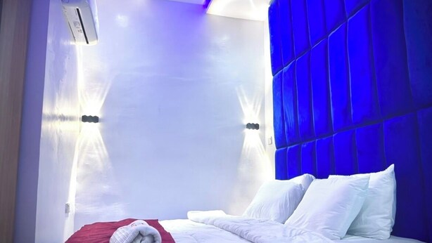 Ein modernes Hotelzimmer mit einem großen Bett, weißer Bettwäsche und einer roten Decke.