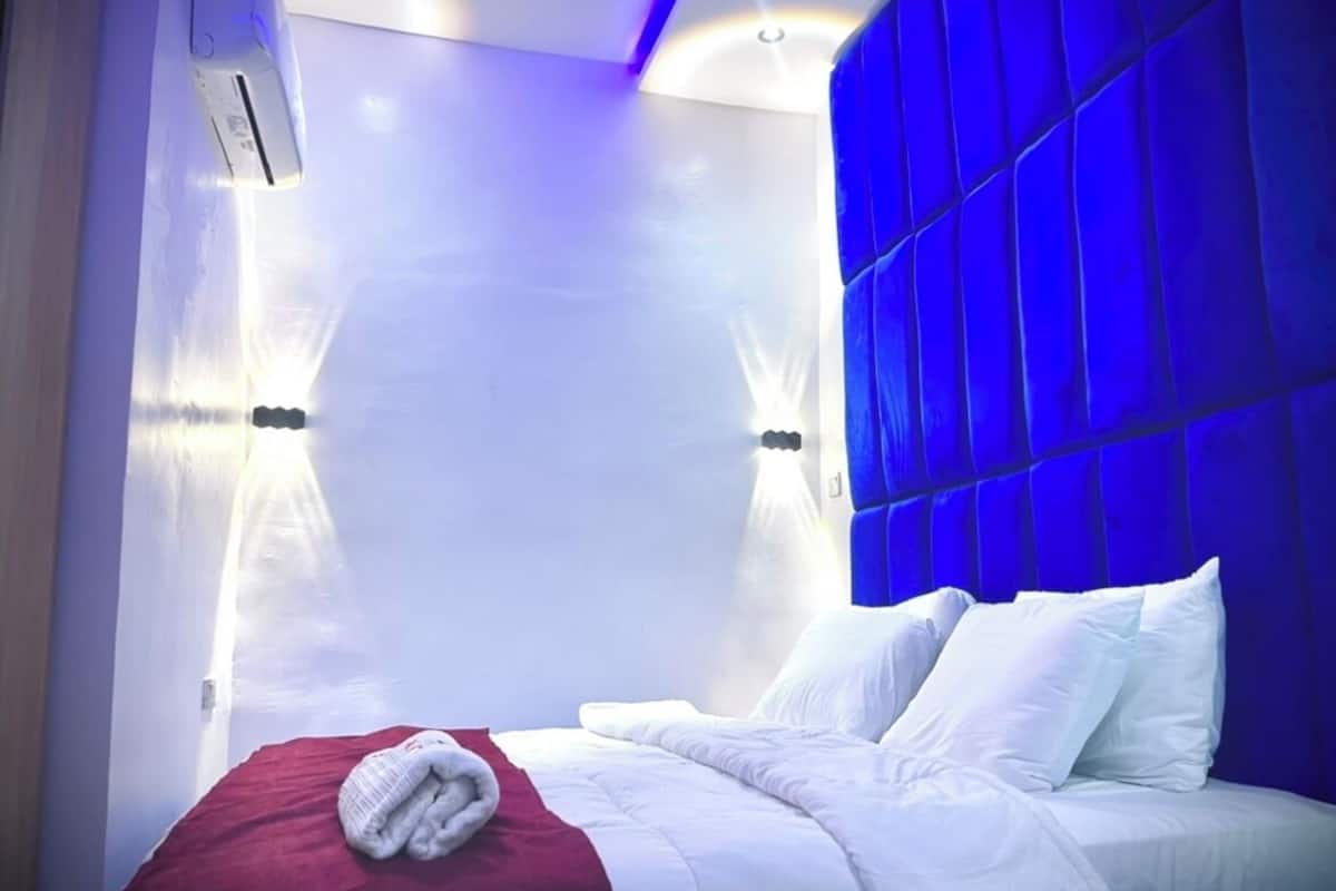 Ein modernes Hotelzimmer mit einem großen Bett, weißer Bettwäsche und einer roten Decke.