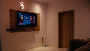 Ein modernes Wohnzimmer mit flachbildfernseher an der Wand, einer Couch und einer Holztür.