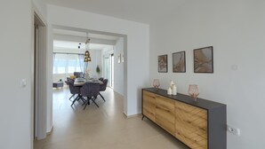 Ein moderner Essbereich mit einem langen Tisch, Stühlen und einer Holztruhe mit Dekorationen.
