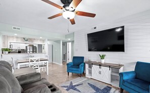 Relax in this stylish living space with a ceiling fan, dining area, and comfortable seating for two.