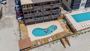 Um hotel com vários andares, área de piscina, espaço para sentar ao ar livre e vista para a praia.