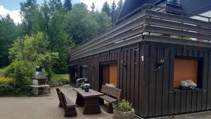 Ein rustikales Holzgebäude mit Terrasse, Sitzgelegenheiten im Freien und einem Grill.