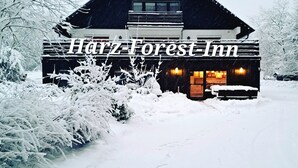 Ein schneebedecktes Gebäude mit der Aufschrift 'Harz-Forest Inn', die den Namen des Hauses angibt.