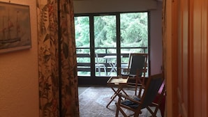 Ein Zimmer mit einem großen Fenster, einem Holzsessel und einem Tisch.