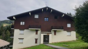 Ein zweigeschossiges Gebäude mit einem geneigten Dach, einem zentralen Eingang und einem kleinen Balkon im Obergeschoss.