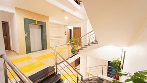 Ein mehrgeschossiges Interieur mit einer zentralen Treppe, einer Tür mit grüner Akzentfarbe und Topfpflanzen.