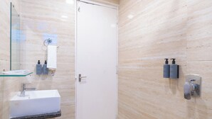 Ein modernes Badezimmer mit einem weißen Waschbecken, einer Glasablage, einer Dusche und einem WC.