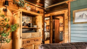 A wooden cabin interior with a large wooden cabinet, a cushioned bench, and a framed picture on the wall.