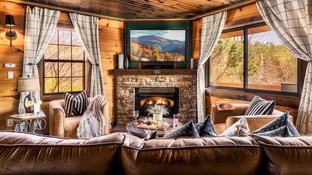 A cozy living room with a stone fireplace, leather sofas, and a flat-screen TV.