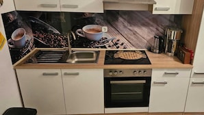 A compact kitchen with a sink, stove, oven, and a coffee machine. - "charmante 2 Zimmer Wohnung in Ansbach" (Ansbach)