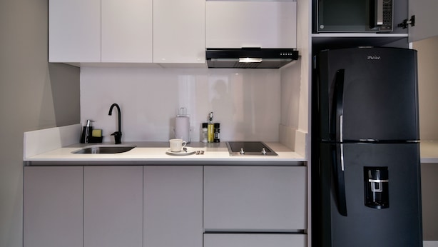 Eine moderne Küche mit einem schwarzen Kühlschrank, einer Mikrowelle, einem Spülbecken und einer Kaffeemaschine.
