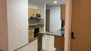 A modern kitchen with wooden cabinets, a microwave, a gas stove, and a granite countertop.