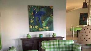 Ein Wohnzimmer mit einer gepolsterten Couchgarnitur in Rautenmuster, einem Holztisch und einem Bild an der Wand.