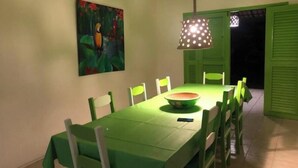 Ein Essbereich mit einem grünen Tisch und Stühlen, einer Hängelampe und einem Bild an der Wand.