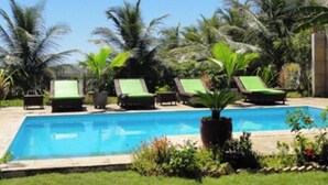 Ein Poolbereich mit Liegestühlen und Palmen.