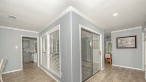 A modern interior with a kitchen in the background, a hallway with a glass door, and a framed picture on the wall. - ~ 3 miles to Kyle Field/TAMU ~ 8 min to Santa’s Wonderland ~  (College Station)