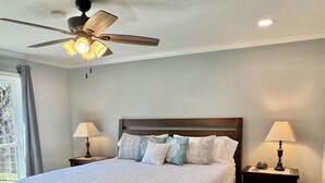 A bedroom with a large bed, two bedside tables with lamps, a ceiling fan, and a window with curtains. - ~ 3 miles to Kyle Field/TAMU ~ 8 min to Santa’s Wonderland ~  (College Station)