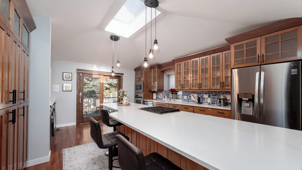 Een moderne keuken met een groot schiereiland, houten kastjes en een dakraam.