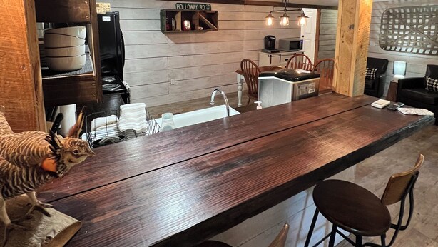 Una cocina rústica con vigas de madera, una barra de madera larga y un letrero que dice "Holloway Rd 197".