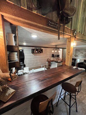 A rustic kitchen with wooden beams, a long wooden bar, and a sign reading "Holloway Rd 197". - The Barn at Canoochee Farms (23 miles from Statesboro and GSU) (Cobbtown)