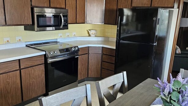 A kitchen with wooden cabinets, a microwave, a stove, and a refrigerator.