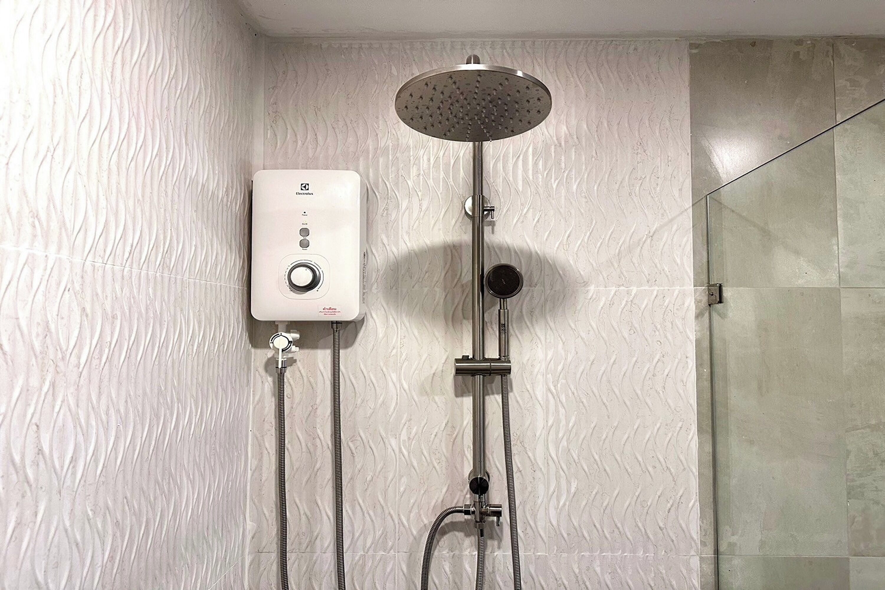 A shower with a handheld showerhead and a wall-mounted control panel.