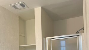 Un baño con cabina de ducha de vidrio, un perchero con una toalla doblada y un estante azul.