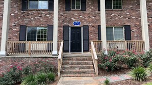 A two-story building with a brick facade, a central entrance with a black door, and a blue sign above the door. - Just Peachy 2BR/2BA apartment in Atlanta with 5G fast WiFi, All to Yourself (Atlanta)