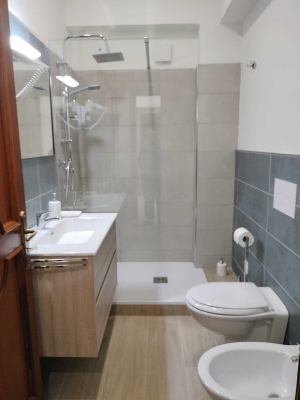 Une salle de bain moderne équipée d’une douche, de toilettes, d’un bidet et d’un lavabo.