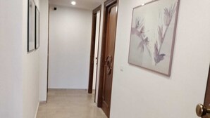 A hallway with a tiled floor, a door with a decorative handle, and a framed picture on the wall. - D&P Suites 2 Salemi (Salemi)