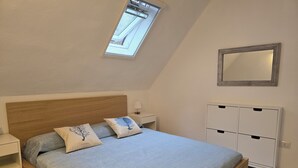 A bedroom with a wooden bed, a nightstand, a bedside table, a wardrobe, and a skylight. - Renovated Villa | Pool | Beach 300m Walk | 4 Guests | Pula Sardinia (Santa Margherita di Pula)