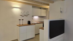 A compact kitchen with white cabinets, a wooden countertop, and a black TV mounted on the wall. - Renovated Villa | Pool | Beach 300m Walk | 4 Guests | Pula Sardinia (Santa Margherita di Pula)