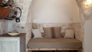 Una habitación acogedora y rústica con una cama empotrada, paredes de piedra y un aparador de madera con vajilla.