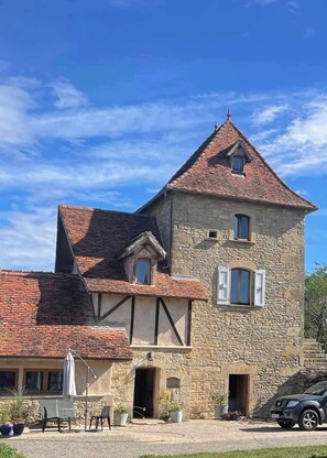 Un bâtiment en pierre doté d’un toit à forte pente, d’un petit balcon et d’une porte donnant sur une entrée abritée.