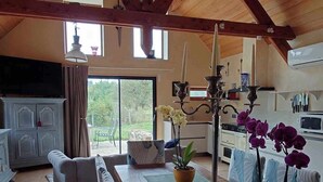 Ein geräumiger Wohnbereich mit hohen Decken, Holzbalken, einem langen Esstisch und Topforchideen.
