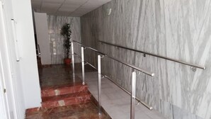 Eine Marmortreppe mit Metallgeländern, die zu einer Empore mit einem Blumentopf führt.