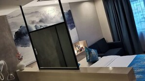 A modern hotel room with a bed, a desk, a chair, and a large window with curtains. - Qinyu Hotel (Haikou)