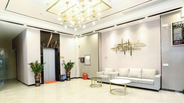 A modern lobby with a white sofa, a round coffee table, and a decorative light fixture. - Qinyu Hotel (Haikou)